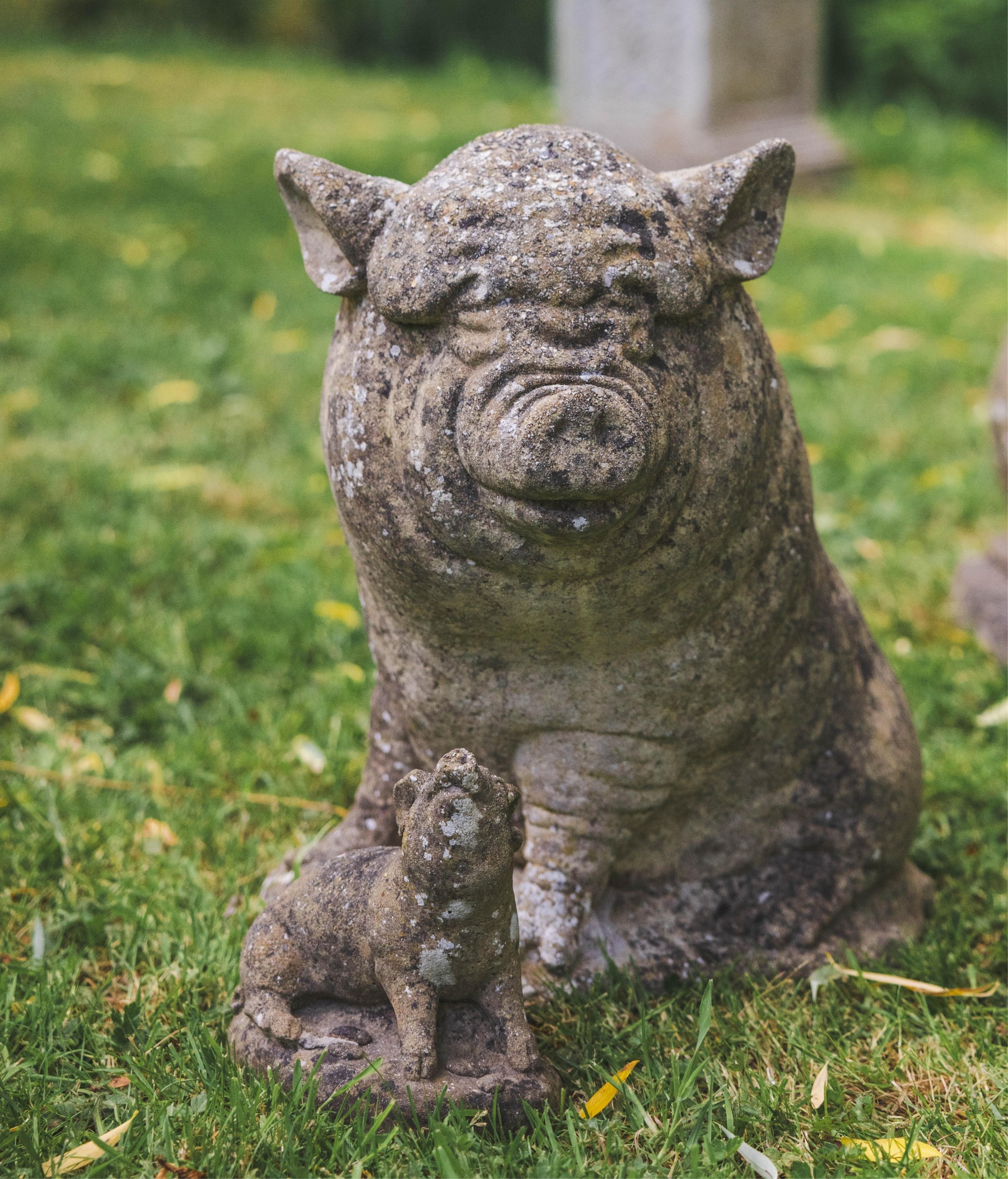 A reconstituted stone pig garden ornament and one smaller pig ornament, larger height 44cm